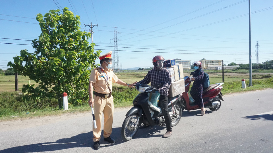 Lực lượng chức năng giải thích cho người dân về quy định ra vào vùng dịch. (Ảnh: Bích Huệ/TTXVN)