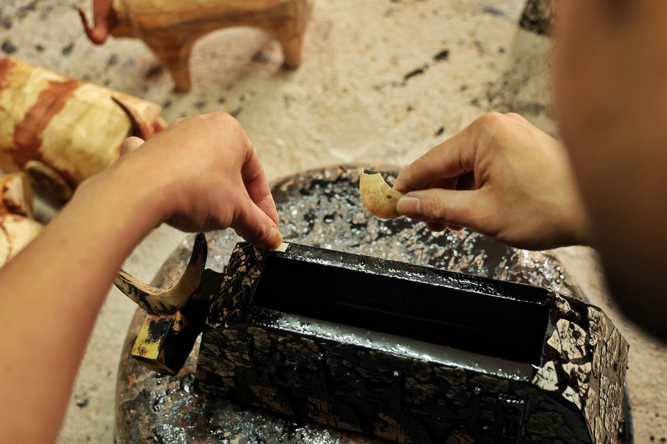 Với bộ sưu tập lần này, chọn sáng tạo nghệ thuật để tri ân mảnh đất quê hương, Tấn Phát đã dành nhiều tâm huyết, tư duy và sự tử tế cho tác phẩm ngay từ khâu chọn nguyên liệu với gỗ, tận dụng vỏ trứng, vỏ trai để khảm, trang trí cho những ‘đứa con’ của mình, như một cách kêu gọi cộng đồng bảo vệ môi trường. (Ảnh: Xuân Mai/Vietnam+)