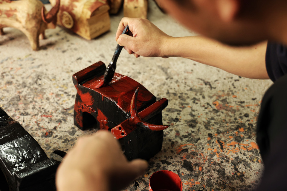 Mỗi chú trâu sẽ được 'mặc' nhiều 'lớp áo.' Vì được làm thủ công hoàn toàn nên mỗi con sẽ là một phiên bản khác biệt với những đường nét, hoa văn, màu sắc, kích thước và tinh thần không giống nhau. (Ảnh: Xuân Mai/Vietnam+)