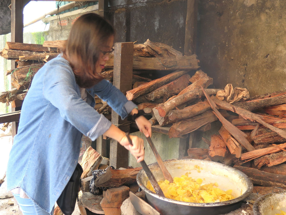 Rim gừng dưới lửa củi cháy nhỏ và phải được đảo đều tay để tránh cháy khét, gừng vón cục. (Ảnh: Mai Trang/TTXVN)