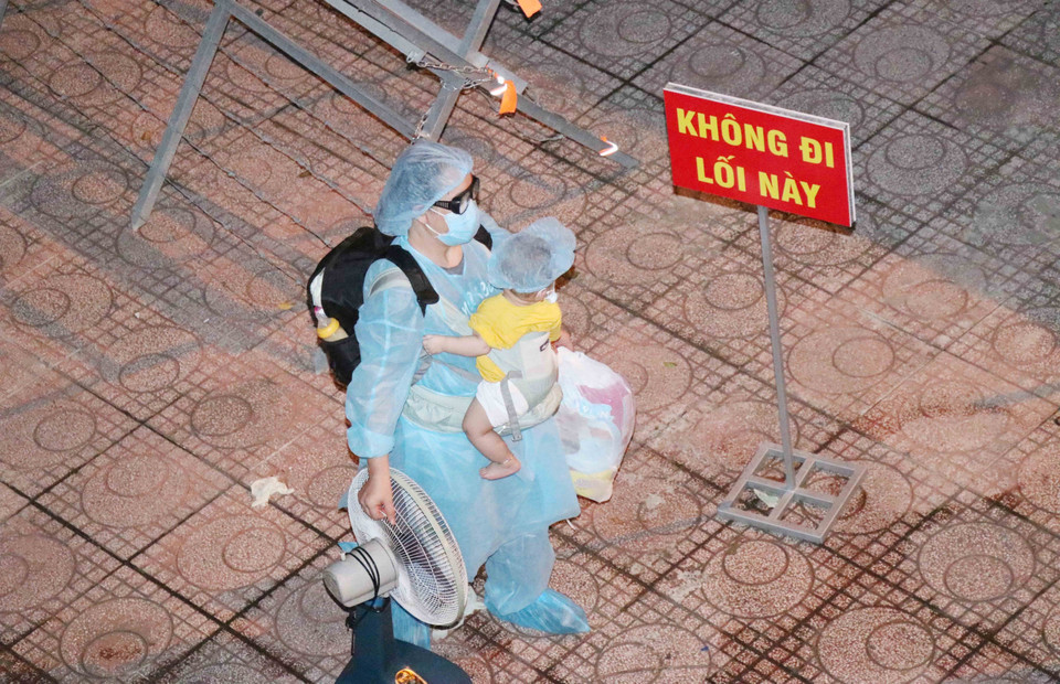 Cháu bé được mẹ bế chờ làm thủ tục nhận phòng trong đêm 11/7. (Ảnh: Xuân Khu)