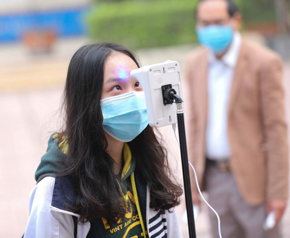 Học sinh lớp 12 trường Trung học phổ thông Kim Liên, quận Đống Đa, thực hiện đo thân nhiệt khi tới trường học trực tiếp từ sáng 4/1/2022. (Ảnh: Thanh Tùng/TTXVN)