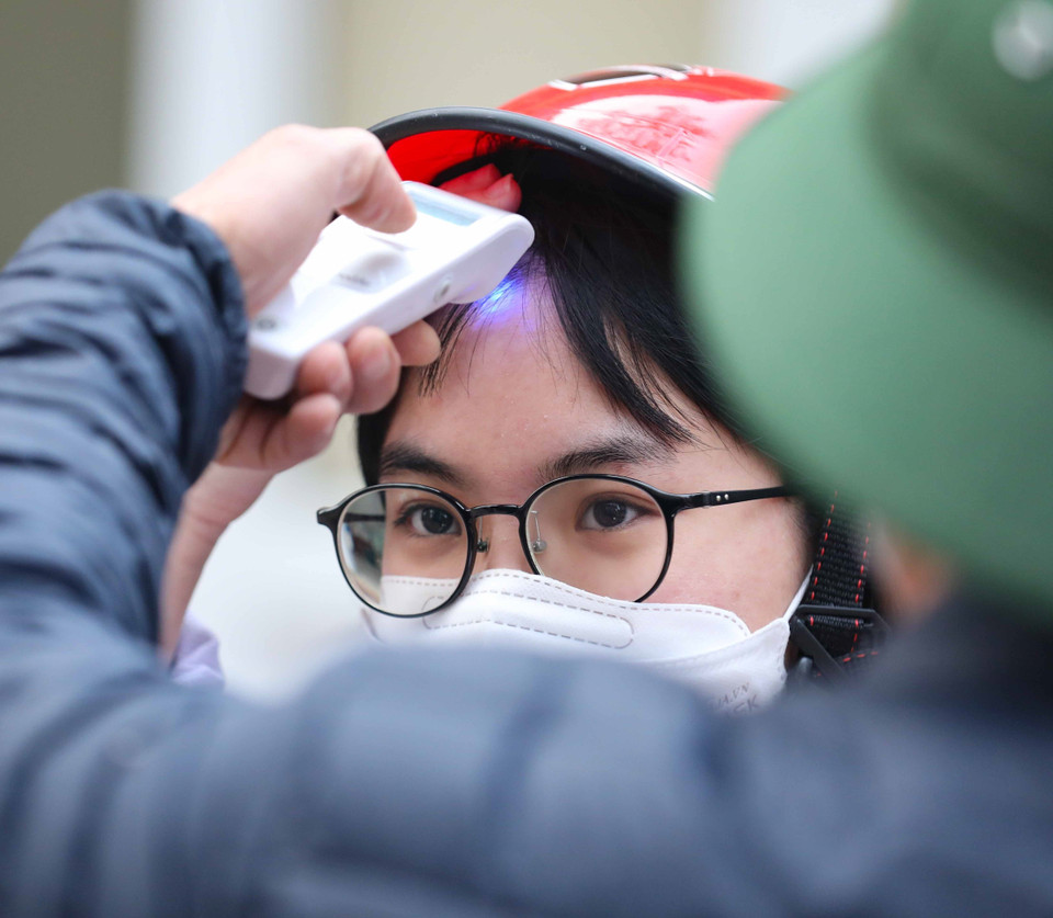 Học sinh lớp 12 trường Trung học phổ thông Kim Liên, quận Đống Đa thực hiện đo thân nhiệt khi tới trường học trực tiếp. (Ảnh: Thanh Tùng/TTXVN)