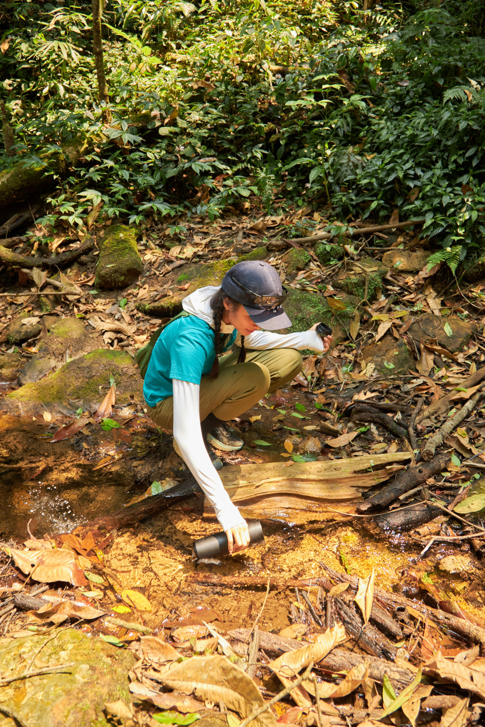 Đến bên một con suối, H'Hen Niê dùng bình múc nước suối uống, vị ngọt mát của nước suối khiến cô vô cùng sảng khoái như nạp thêm năng lượng cho hành trình tiếp theo. (Ảnh: CTV/Vietnam+)