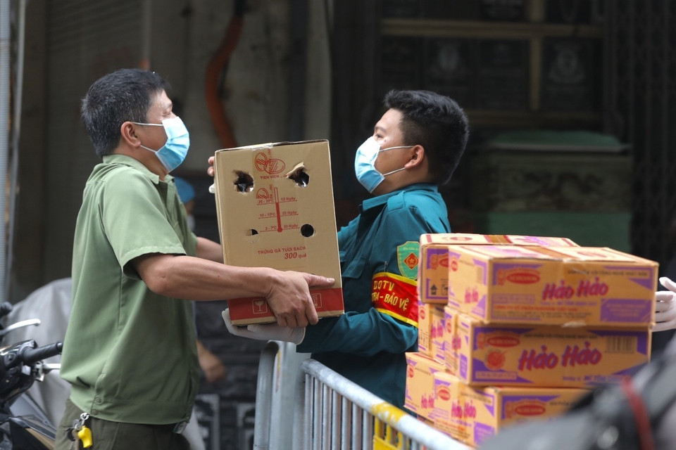 Lực lượng chức năng phường Lý Thái Tổ (quận Hoàn Kiếm) vận chuyển mỳ tôm và trứng hỗ trợ các hộ trong khu vực phong tỏa tạm thời. (Ảnh: Minh Quyết/TTXVN)