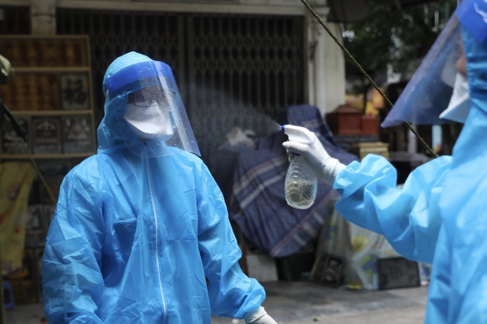 Nhân viên y tế khử khuẩn sau khi hoàn thành lấy mẫu cho 41 trường hợp trong khu vực phong tỏa tạm thời phố Hàng Mắm (phường Lý Thái Tổ, quận Hoàn Kiếm). (Ảnh: Minh Quyết/TTXVN)