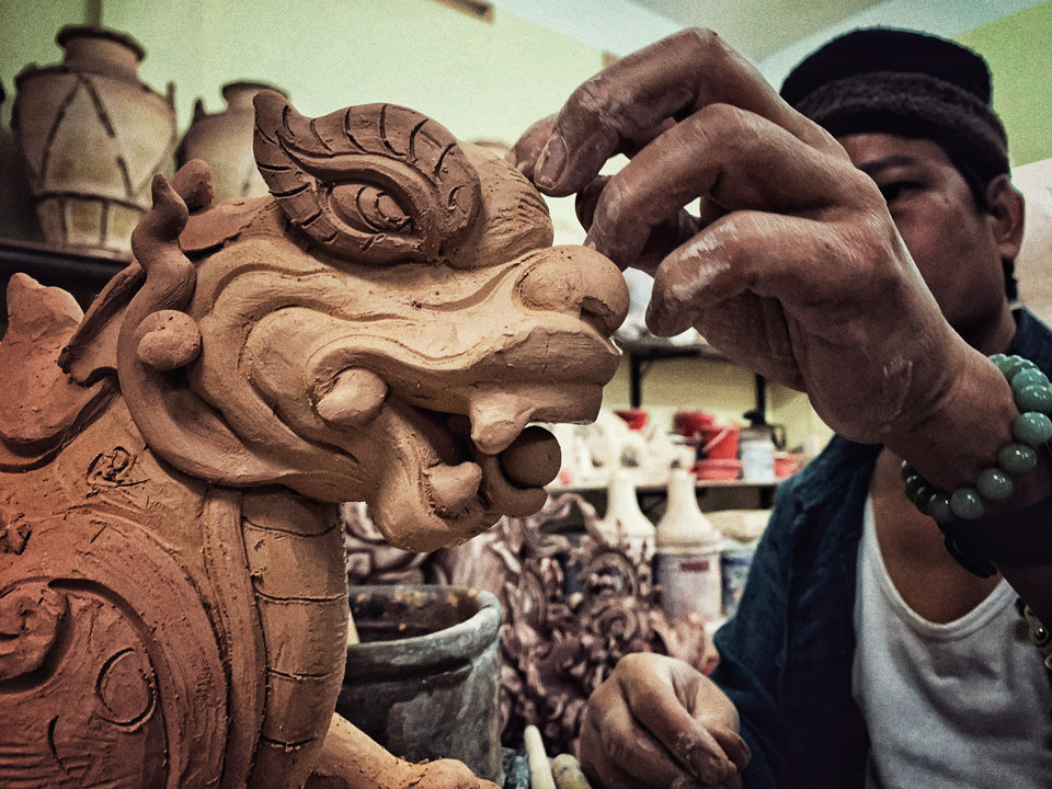 'Kỹ thuật làm gốm của tôi là hoàn toàn dựa trên kỹ thuật của gốm Bát Tràng cổ nhưng trong quá trình làm việc, có những anh em sẽ phục chế còn tư tưởng của tôi là người bảo tồn nhưng phải phát triển, nên mặc dù những sản phẩm của tôi làm nhìn có vẻ cổ điển nhưng đều là sáng mới của tôi, từ kiểu dáng cho đến chất liệu, màu men và nội dung, nhưng vẫn dựa trên cơ sở xương da truyền thống của Bát Tràng,' nghệ nhân Trần Tước chia sẻ. (Ảnh: Xuân Mai/Vietnam+)