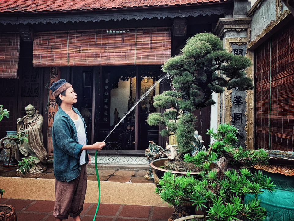 Một buổi sớm ngày cận Tết, vận chiếc quần đũi sắn ống thấp ống cao với đôi tông lào ngả màu, nghệ nhân ưu tú Trần Nam Tước say sưa tưới tắm cho vườn tiểu cảnh trên sân thượng. (Ảnh: Xuân Mai/Vietnam+)