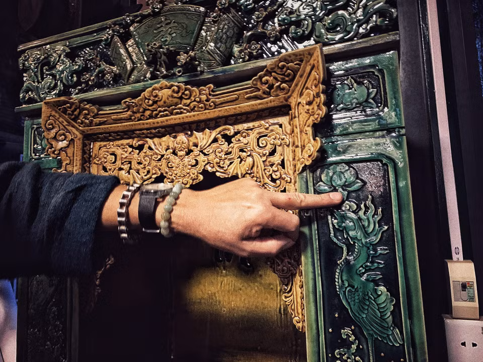 Với dòng men xanh ngọc được làm từ thủy tinh này, anh cũng phải tính toán kỹ để men chỉ chảy xuống tới chân khám thờ. Các họa tiết đều được đắp thủ công 'tay bo.' (Ảnh: Xuân Mai/Vietnam+)