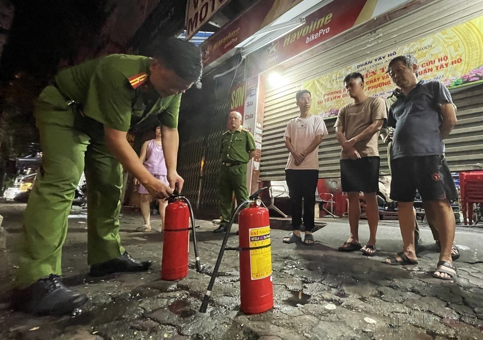 Tổ liên gia số 05, phường Bưởi, quận Tây Hồ (Hà Nội) nghe cán bộ công an hướng dẫn cách sử dụng bình chữa cháy. (Ảnh: Lâm Khánh/TTXVN)