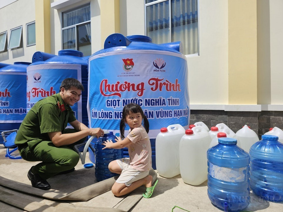 Cán bộ, chiến sỹ Công an tỉnh Bến Tre hỗ trợ người dân xã An Định, huyện Mỏ Cày Nam lấy nước ngọt miễn phí về sinh hoạt do ảnh hưởng bởi hạn hán và xâm nhập mặn. (Ảnh: Chương Đài/TTXVN)
