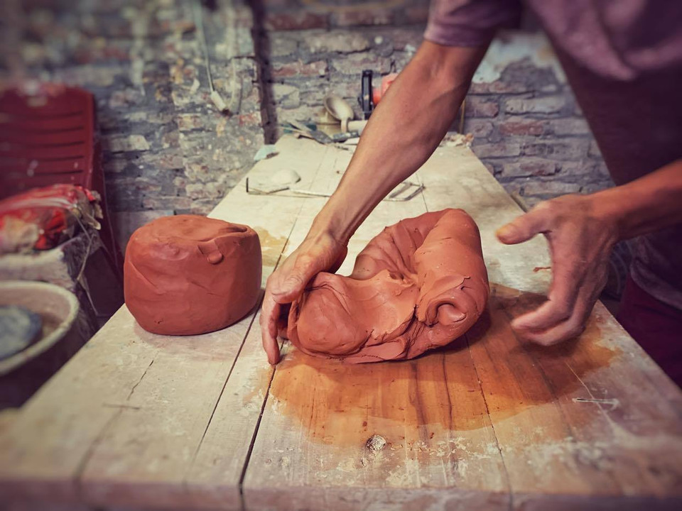 Điểm khác biệt của nghệ nhân Anh Đạo là anh hoàn toàn sử dụng phương thức truyền thống: làm gốm trên bàn xoay theo kiểu vuốt-nặn-vẽ. Và đây là công đoạn vò đất. Đất được vò để đẩy khí, đất vò càng kỹ càng tốt. (Ảnh: Xuân Mai/Vietnam+)