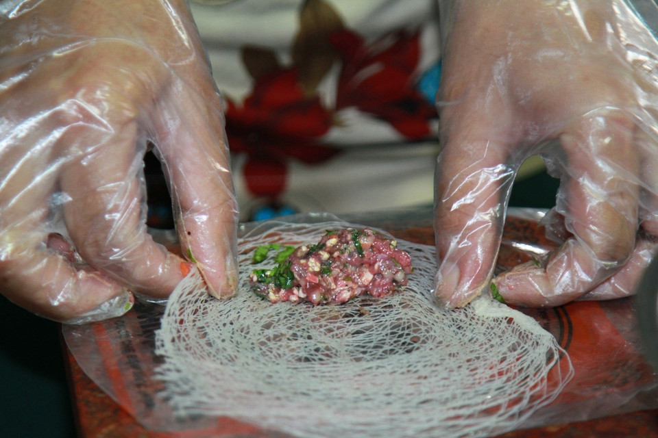 Sau khi ướp gia vị khoảng 10 phút, cuốn nguyên liệu với bánh đa thành những chiếc ram xinh xắn. (Ảnh: Xuân Mai/Vietnam+)