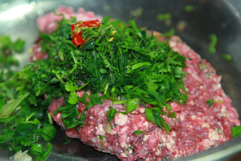 Trộn nguyên liệu với các loại rau gia vị như hành, răm, húng, mùi tàu, lá lốt, ớt... (Ảnh: Xuân Mai/Vietnam+)