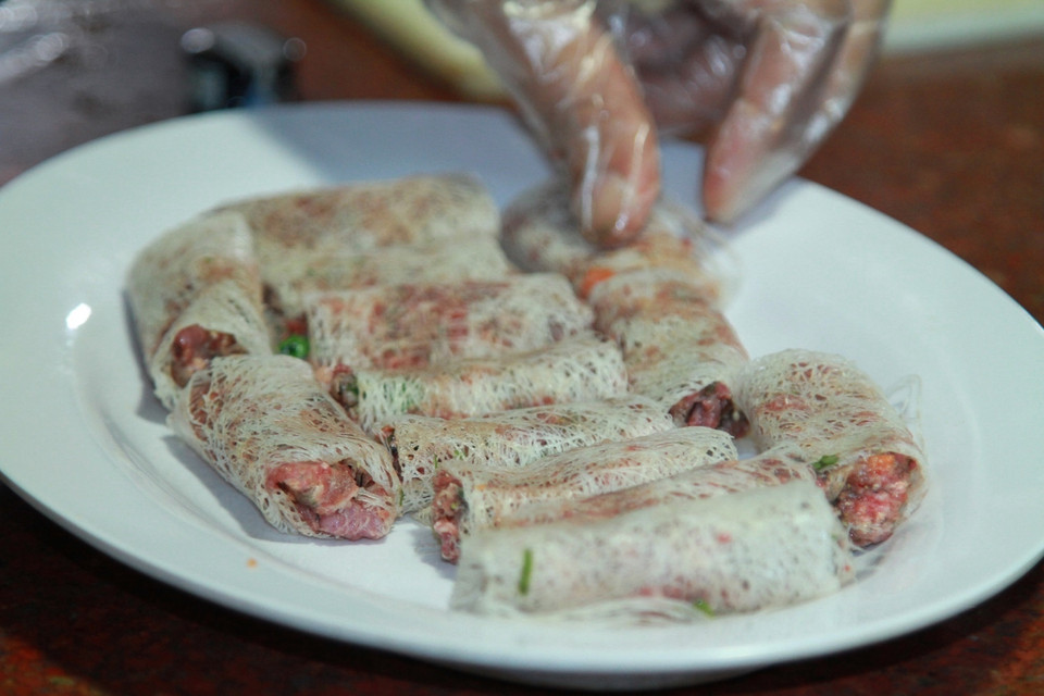Điều khác biệt của món ăn này ngoài hương vị thơm ngon của đẻn quyện với hương vị của các loại gia vị, bánh đa dùng để cuốn cũng được làm ở làng bánh tráng Tân An của Quảng Bình, dẻo dai và khi rán lên, ram đẻn vàng giòn, thơm ngon hơn. (Ảnh: Xuân Mai/Vietnam+)