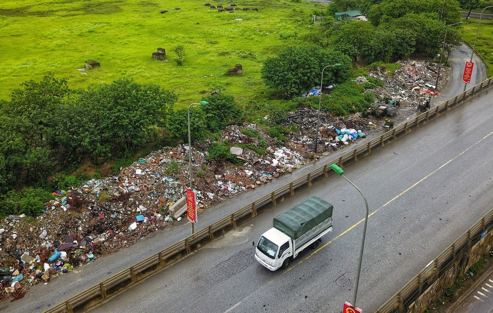 Bãi rác khổng lồ nằm ngay chân cầu vượt xã An Khánh, lối rẽ từ đường gom Đại lộ Thăng Long. (Ảnh: Thành Đạt/TTXVN)