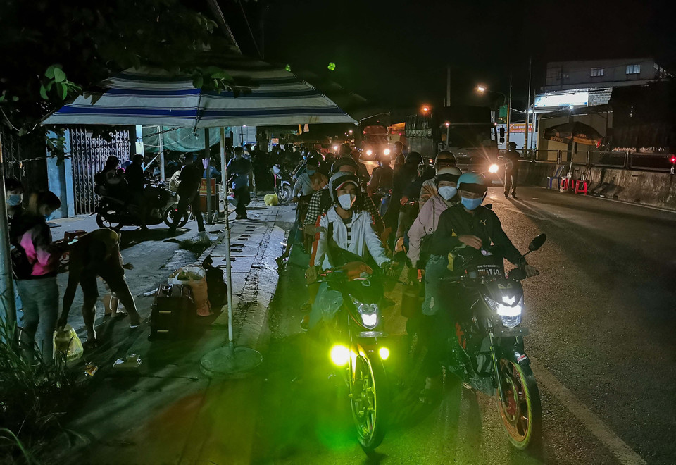 Người dân đi xe máy về quê chờ tại chốt kiểm soát dịch COVID-19 của tỉnh Hậu Giang trên Quốc lộ 1A. (Ảnh: Thanh Liêm/TTXVN)