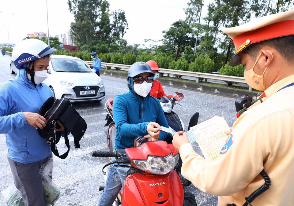 Lực lượng chức năng chốt kiểm soát dịch tại ngã 3 Cầu Giẽ, huyện Phú Xuyên hướng từ Hà Nam về Hà Nội trên tuyến Quốc lộ 1A yêu cầu người tham gia giao thông dừng phương tiện để kiểm tra giấy tờ và khai báo y tế. (Ảnh: Phạm Kiên/TTXVN)
