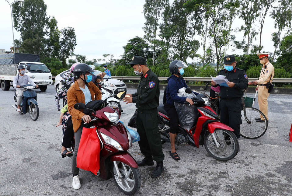 Lực lượng chức năng chốt kiểm soát dịch tại ngã 3 Cầu Giẽ, huyện Phú Xuyên hướng từ Hà Nam về Hà Nội trên tuyến Quốc lộ 1A yêu cầu người tham gia giao thông dừng phương tiện để kiểm tra giấy tờ và khai báo y tế. (Ảnh: Phạm Kiên/TTXVN)