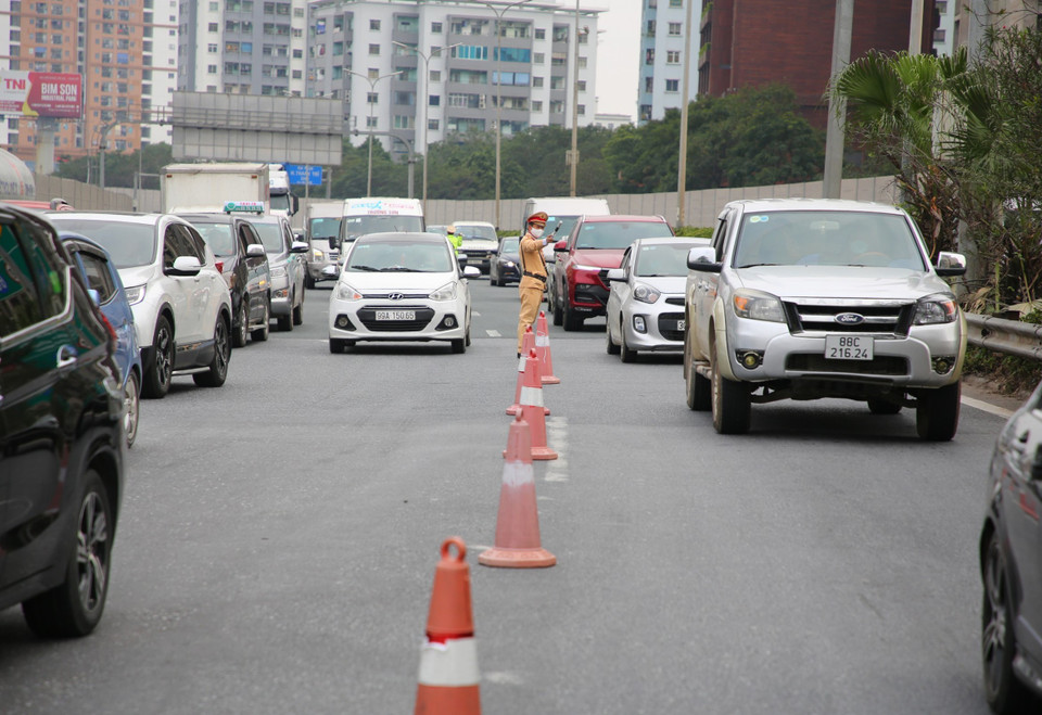 Lực lượng cảnh sát giao thông lên phương án đặt cọc tiêu tại đoạn cuối cao tốc, đồng thời hướng dẫn các phương tiện đi ra khu vực đường gom để giảm tải cho tuyến đường chính. (Ảnh: Phạm Kiên/TTXVN)