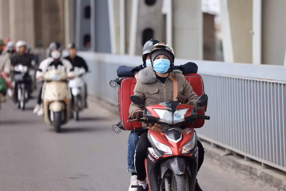 Người dân đeo thêm găng tay và mũ áo ấm, 'lỉnh kỉnh' hành lý về quê đón Tết trong thời tiết se lạnh. (Ảnh: Minh Sơn/Vietnam+)
