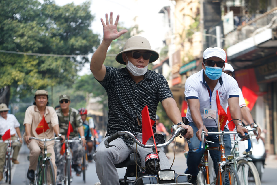 Thành viên các câu lạc bộ đạp xe diễu hành với cờ Tổ quốc phía trước. (Ảnh: Hoàng Việt/TTXVN)