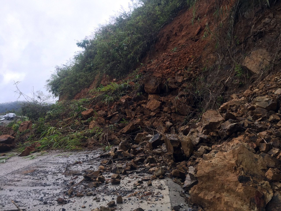 Đất đá bị cuốn trôi trên mặt đường gây khó khăn cho các phương tiện tham gia giao thông tại km 109 trên Quốc lộ 279. (Ảnh: Phan Tuấn Anh/TTXVN)