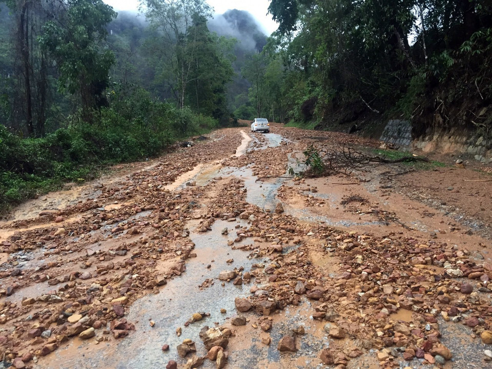 Đất đá bị cuốn trôi trên mặt đường gây khó khăn cho các phương tiện tham gia giao thông tại km 109 trên Quốc lộ 279. (Ảnh: Phan Tuấn Anh/TTXVN)