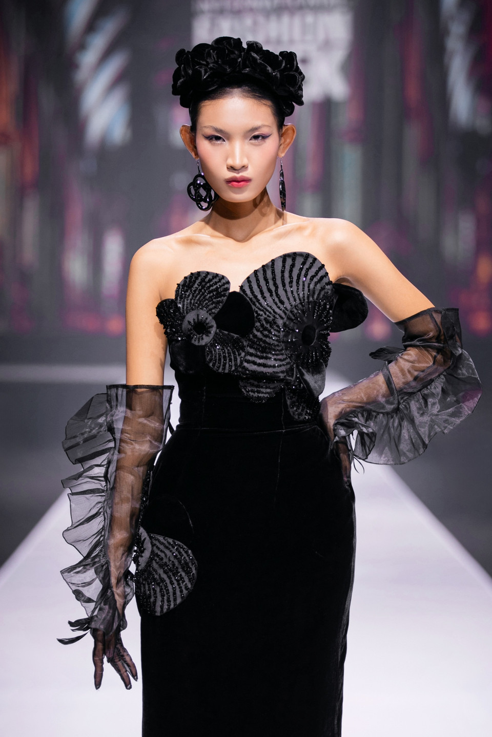 Đặc biệt, khép lại bộ sưu là màn trình diễn của Quán quân The Face Vietnam 2023 - Huỳnh Tú Anh trong vai trò vedette. Với những bước catwalk tự tin, Tú Anh diện thiết kế đầm nhung cúp ngực quyến rũ, kết hợp cùng găng tay voan dài và bờm nhung tinh tế. Sự hòa quyện giữa nét đẹp hiện đại, thần thái cuốn hút và phong cách sang trọng tựa một quý cô đã làm nổi bật tinh thần của bộ sưu tập, để lại ấn tượng khó quên. (Ảnh: PV/Vietnam+)