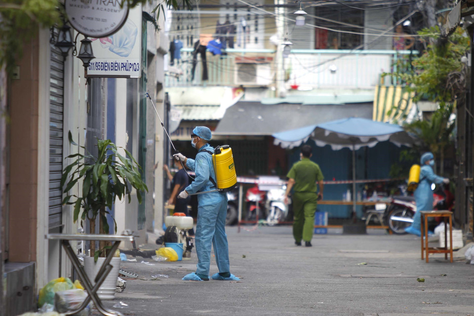 Các lực lượng chức năng phun xịt, khử khuẩn toàn bộ khu vực phong tỏa cách ly tại hẻm 611 đường Điện Biên Phủ, phường 1, Quận 3. (Ảnh: Thanh Vũ/TTXVN)