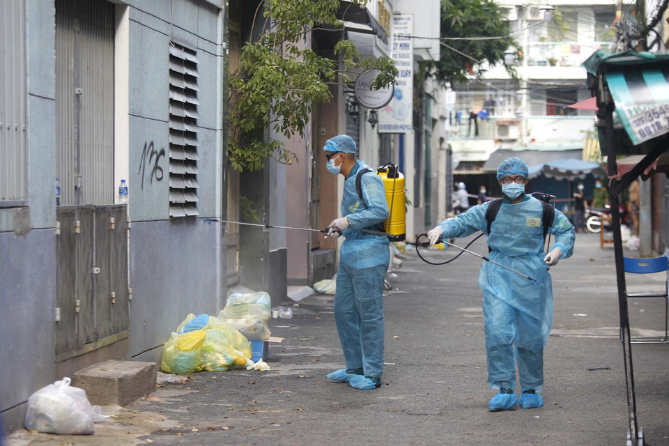 Các lực lượng chức năng phun xịt, khử khuẩn toàn bộ khu vực phong tỏa cách ly tại hẻm 611 đường Điện Biên Phủ, phường 1, Quận 3. (Ảnh: Thanh Vũ/TTXVN)