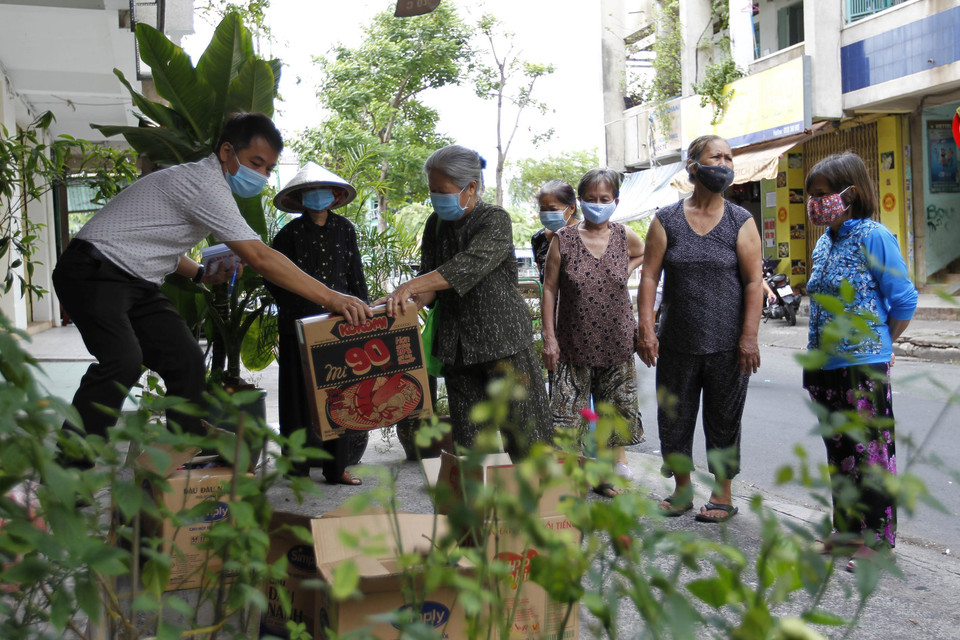 Các "mạnh thường quân" tranh thủ trao tặng quà cho người già, hộ nghèo tại chung cư Trần Quốc Thảo trước giờ thực hiện giãn cách. (Ảnh: Thanh Vũ/TTXVN)