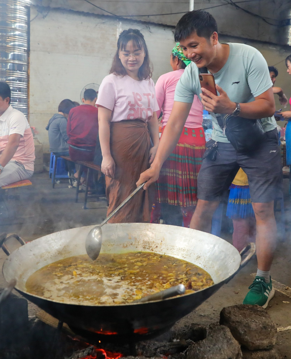 Du khách trải nghiệm nấu món ăn truyền thống của bà con vùng cao - món thắng cố. (Ảnh: Hoàng Hiếu/TTXVN)