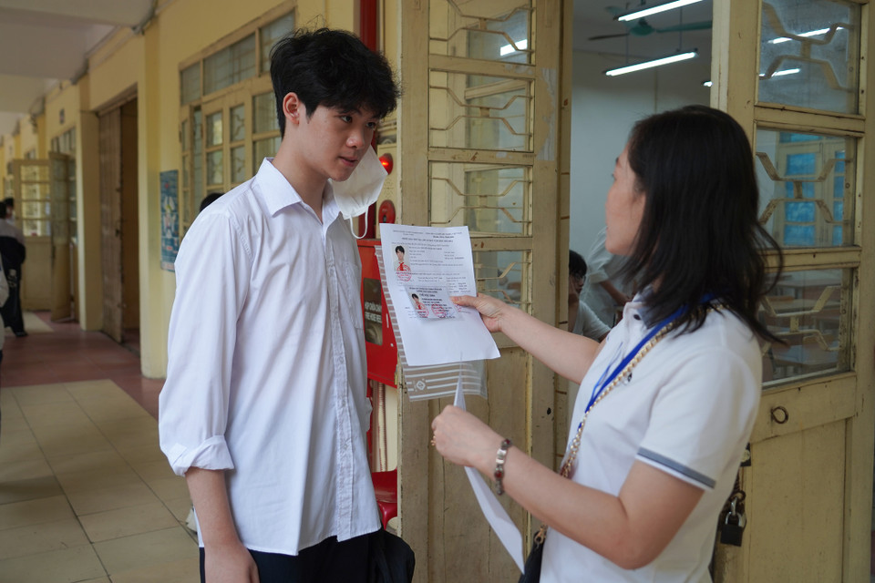 Cán bộ coi thi kiểm tra căn cước công dân của thí sinh trước khi vào phòng thi. (Ảnh: PV/Vietnam+)