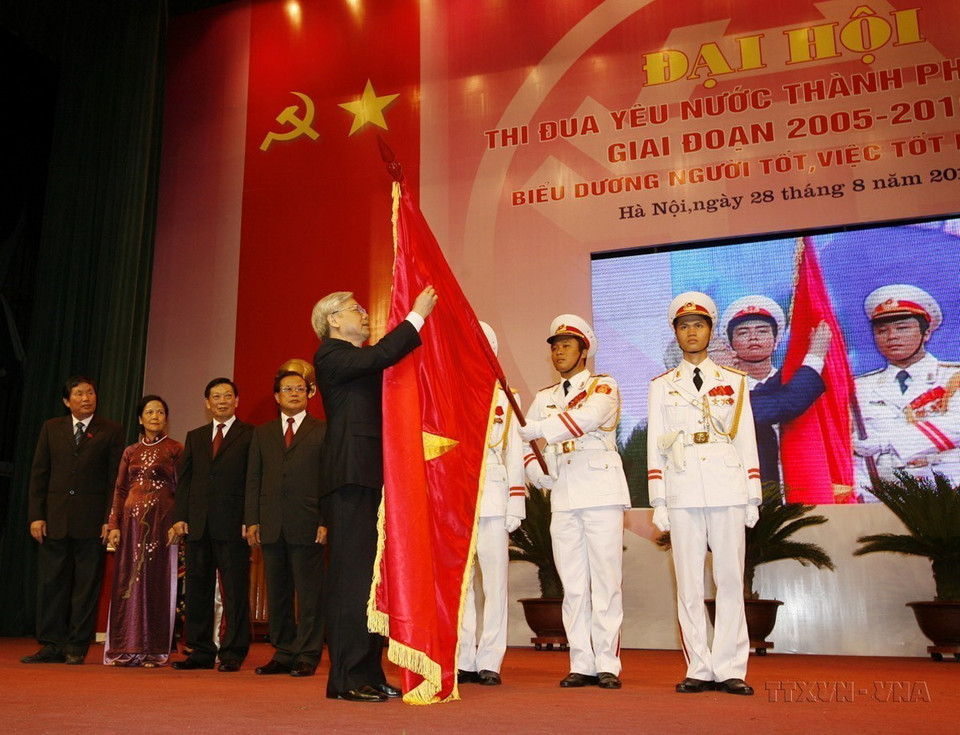 Chủ tịch Quốc hội Nguyễn Phú Trọng gắn Huân chương Sao Vàng lên lá cờ truyền thống của thành phố Hà Nội tại Đại hội thi đua yêu nước thành phố giai đoạn 2005 - 2010. (Ảnh: Trí Dũng/TTXVN)