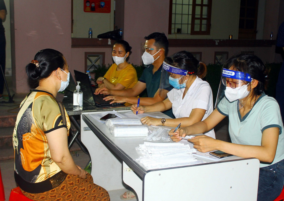  Người dân xã Hưng Đông, thành phố Vinh (Nghệ An) khai báo thông tin trước khi lấy mẫu xét nghiệm COVID-19 vào tối ngày 20/6. (Ảnh: Tá Chuyên/TTXVN)