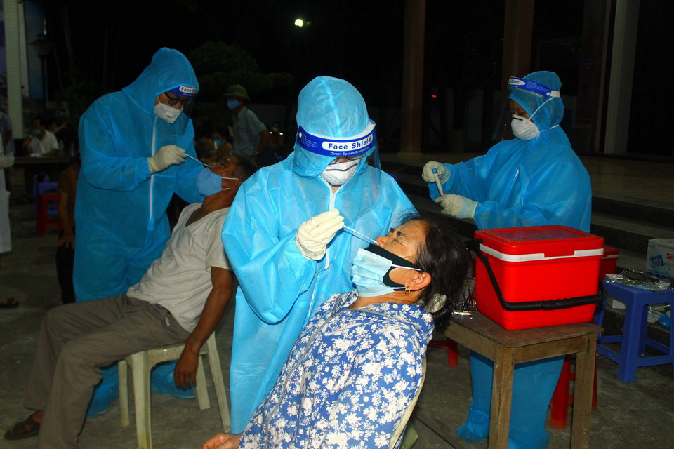 Cán bộ y tế lấy mẫu xét nghiệm cho người dân xã Hưng Đông, thành phố Vinh (Nghệ An) vào tối 20/6. (Ảnh: Tá Chuyên/TTXVN)