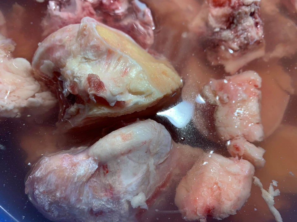 Nguyên liệu để làm món phở bò hương vị Hà Nội: 1kg xương ống bò, 500gr bắp bò hoa để làm bò tái (hoặc thêm gù bò để làm món bò chín), 1 củ gừng to, 2 bông đại hồi, 2 thảo quả, 1 nhánh nhỏ quế, 1gr hạt mùi già, 1gr tiểu hồi, 5 nụ đinh hương, 10gr tiêu sọ, 20gr sá sùng (nếu có nước phở có vị ngọt thơm tự nhiên), húng quế, hành tươi, hành tây 2 củ; đường phèn, hạt nêm, gia vị, muối, giấm, bánh phở. Sơ chế: Xương bò mua về ngâm trong nước muối và giấm khoảng 2 tiếng cho sạch mùi tanh hôi.(Ảnh: Mai Mai/Vietnam+)