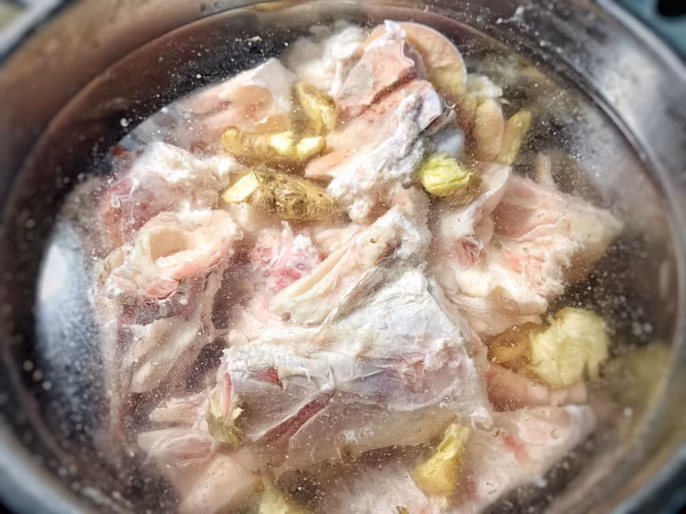 Xương ống bò sau khi ngâm, rửa sạch sẽ cho vào nồi nước đun sôi cùng gừng và 1 muỗng canh muối đun khoảng 10 phút thì vớt ra, rửa với nước lạnh cho sạch. Cách này sẽ giúp loại bỏ được hoàn toàn mùi hôi bò. (Ảnh: Mai Mai/Vietnam+)