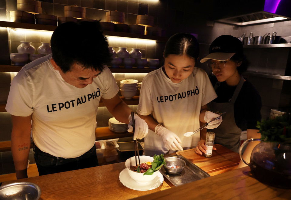 Các đầu bếp nhà hàng Pot Au Pho cùng chuẩn bị một tô phở phục vụ thực khách. (Ảnh: Hồng Đạt/TTXVN)