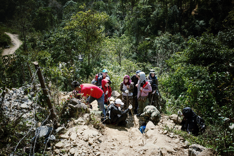 Tháng Hai mà trời nắng chang, mới qua con dốc dựng đứng đầu tiên nhưng một thành viên trong đoàn bị tụt huyết áp, mặt mũi tái mét, thở không ra hơi. Biết không thể gắng gượng nên thành viên này đành dừng cuộc. (Ảnh: Gia Cương/Vietnam+)