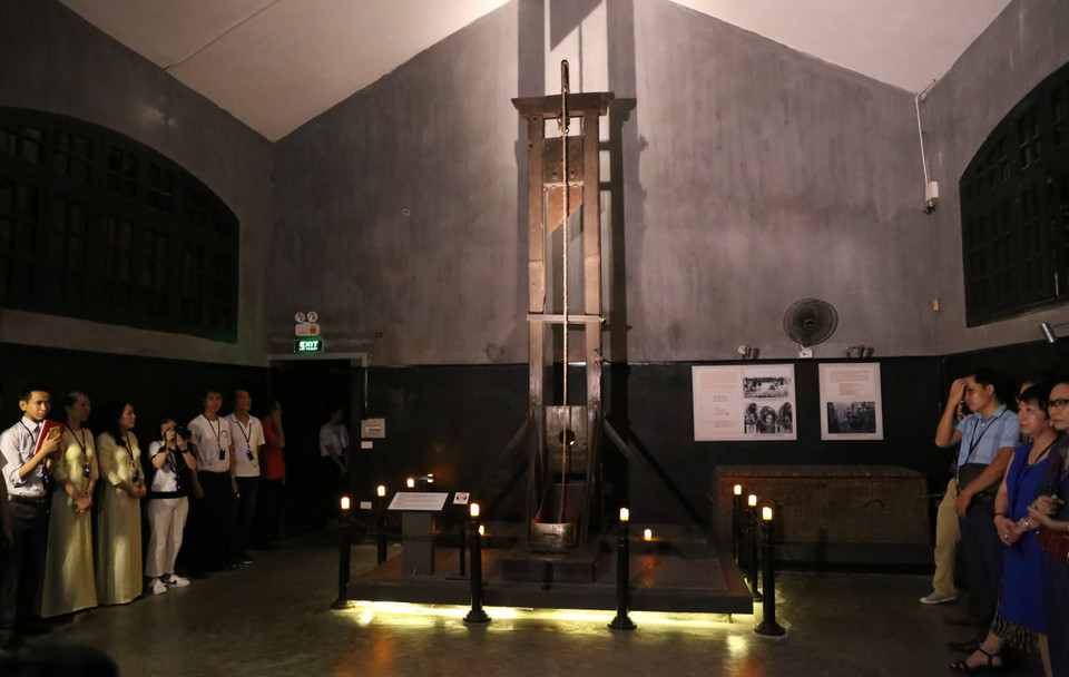 Du khách nghe giới thiệu về chiếc máy chém trong Khu di tích. (Ảnh: Hoàng Hiếu/TTXVN)