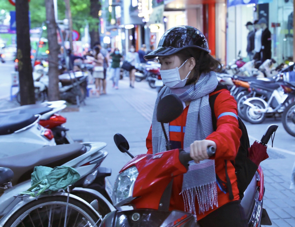 Một bạn trẻ đã trang bị cả áo rét, khăn ấm khi phải di chuyển ra ngoài trời. (Ảnh: Hoàng Hiếu/TTXVN)