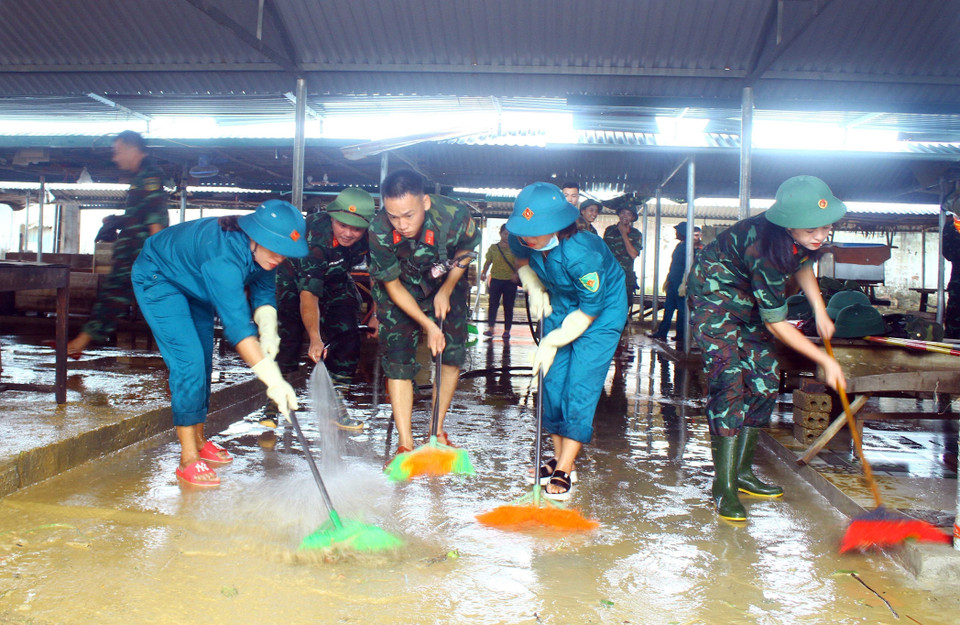 Lực lượng quân đội, dân quân tự vệ đẩy bùn đất, tổng dọn vệ sinh tại chợ xã Thanh Mỹ (huyện Thanh Chương, Nghệ An).(Ảnh: Tá Chuyên/TTXVN)