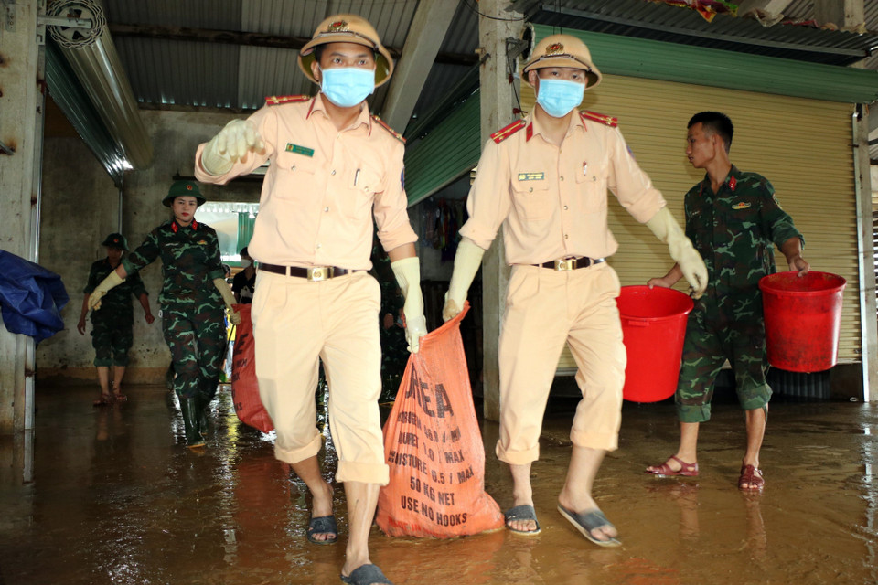 Cán bộ chiên sỹ Công an huyện Thanh Chương hỗ trợ người dân vệ sinh môi trường sau lũ. (Ảnh: Tá Chuyên/TTXVN)