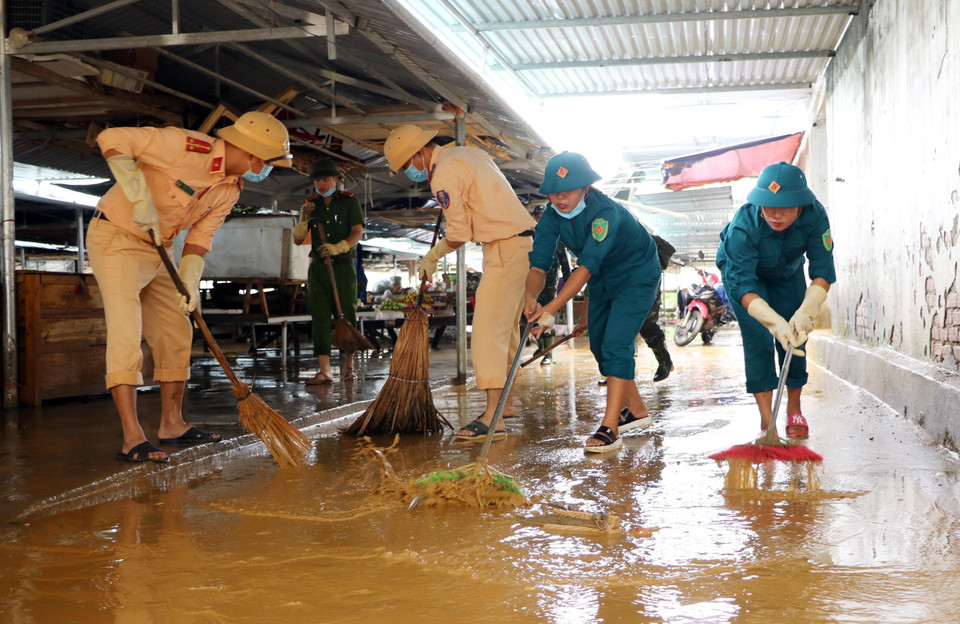 Lực lượng Công an huyện Thanh Chương cùng dân quân tự vệ địa phương đẩy bùn đất, tổng dọn vệ sinh tại chợ xã Thanh Mỹ (huyện Thanh Chương, Nghệ An).(Ảnh: Tá Chuyên/TTXVN)