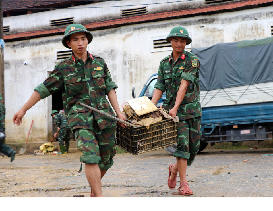 Cán bộ chiến sỹ Sư đoàn 324 thu gom rác, dọn vệ sinh sau lũ tại xã Thanh Mỹ (huyện Thanh Chương, Nghệ An).(Ảnh: Tá Chuyên/TTXVN)