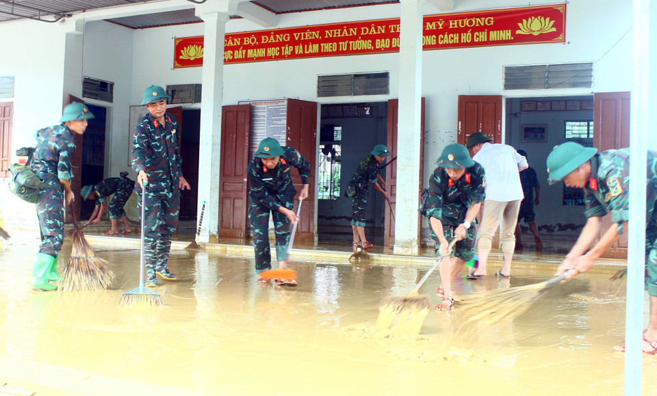 Cán bộ chiến sỹ Sư đoàn 324 đẩy bùn đất, vệ sinh tại nhà văn hóa thôn Mỹ Hương (xã Thanh Mỹ, huyện Thanh Chương). (Ảnh: Tá Chuyên/TTXVN)