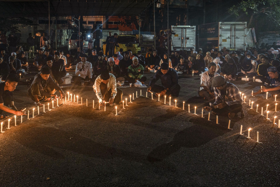 Ít nhất 125 người đã thiệt mạng, 320 người bị thương sau một vụ xô đẩy, giẫm đạp giữa đám đông hỗn loạn trong trận bóng giữa hai câu lạc bộ Arema FC và Persebaya Surabaya tại giải Vô địch quốc gia Indonesia trên sân Kanjuruhan ở tỉnh Đông Java, tối 1/10/2022. Chủ tịch Liên đoàn Bóng đá thế giới (FIFA) Gianni Infantino gọi đây là cú sốc với bóng đá thế giới và là ngày đen tối đối với thể thao. Trong ảnh: Thắp nến tưởng niệm các nạn nhân thảm kịch. (Ảnh: AFP/TTXVN)