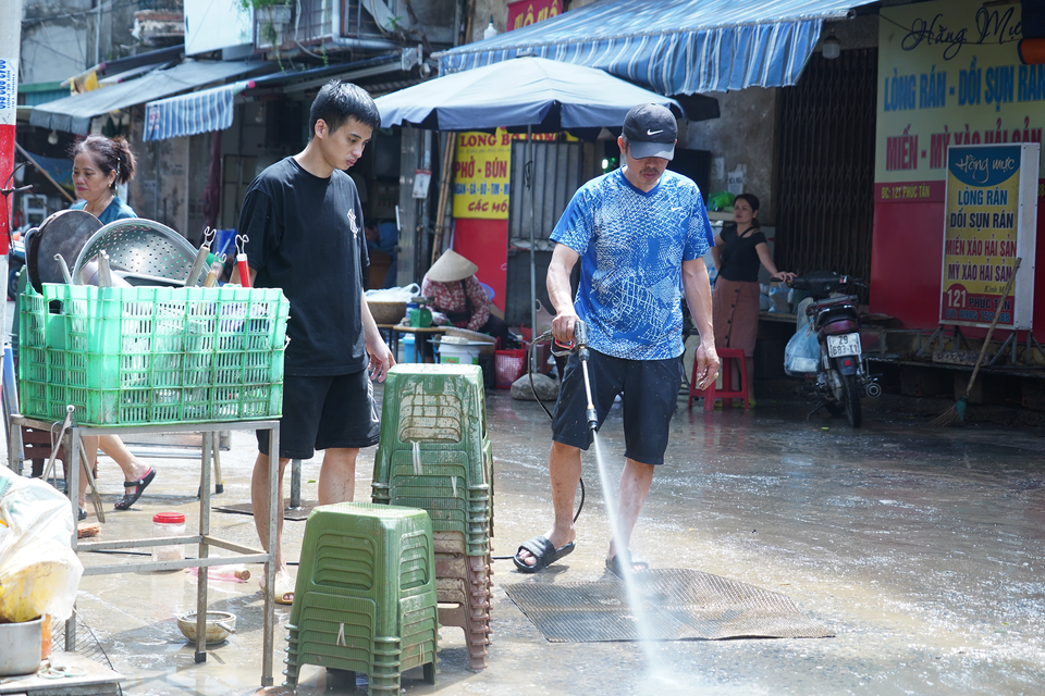 Người dân phun nước rửa sạch bùn đất bám trên các đồ dùng vật dụng trong nhà. (Ảnh: Việt Anh/Vietnam+)